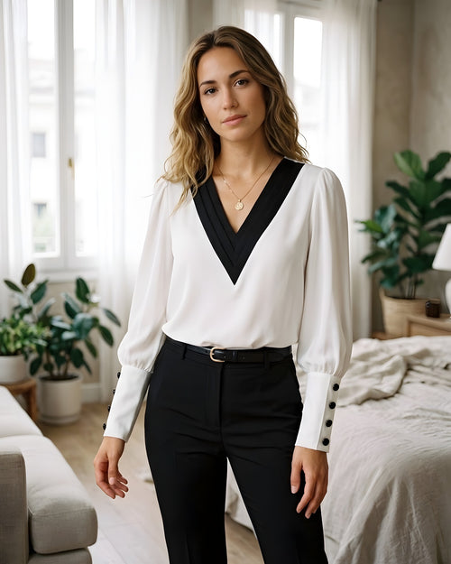 Blusa blanca con escote en V ribeteado en negro y puños de botones